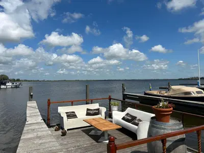 a dock with two chairs and a table and a boat at Holiday Home Campi 400 by Interhome in Uitgeest