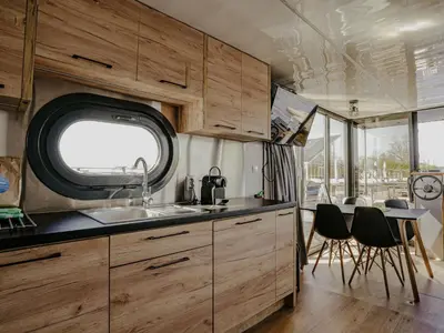 a kitchen with wooden cabinets and a table and chairs at Holiday Home Campi 400 by Interhome in Uitgeest
