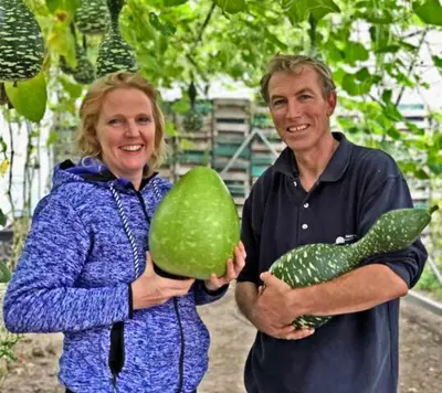 a man and a woman holding a green vegetable at Hotelhuisje Warmenhuizen #C in Warmenhuizen
