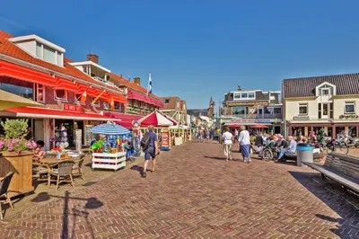 a group of people walking down a street with buildings at Hotelhuisje Warmenhuizen #C in Warmenhuizen