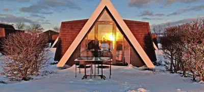 a glass house in the snow with the sun in the window at Hotelhuisje Warmenhuizen #D in Warmenhuizen