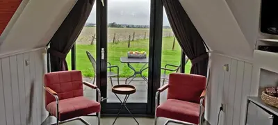 a room with two chairs and a table with a view of a field at Hotelhuisje Warmenhuizen #E in Warmenhuizen