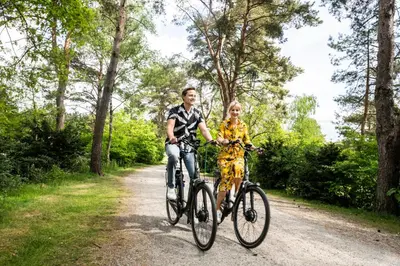 a man and a woman riding bikes down a dirt road at De Krakeling in Zeist