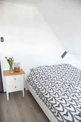 a bedroom with a bed and a table with a vase of flowers at Bed and Wine Nonsolovino in Reeuwijk
