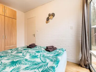 a bedroom with a bed with a blue and white blanket at Holiday Home in Noordwijkerhout near Lake in Noordwijkerhout