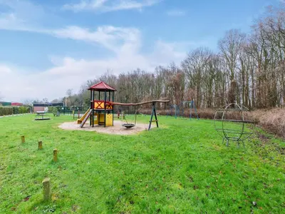 a park with a playground with a slide and swings at Holiday Home in Noordwijkerhout near Lake in Noordwijkerhout