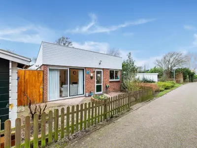 a small brick house with a wooden fence at Holiday Home in Noordwijkerhout near Lake in Noordwijkerhout