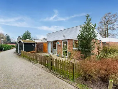 a brick house with a fence next to a road at Holiday Home in Noordwijkerhout near Lake in Noordwijkerhout