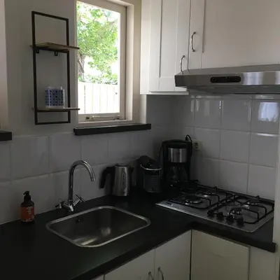 a kitchen with a sink and a stove and a window at Huize Beemsterlaan in Bergen