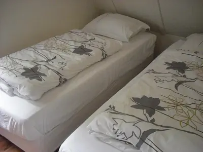 two beds with white sheets and flowers on them at Huize Beemsterlaan in Bergen