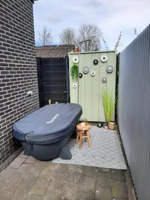 a bath tub sitting in front of a building at Vakantievilla 10 km van strand honden welkom omheinde tuin sauna buitenbad in Dirkshorn