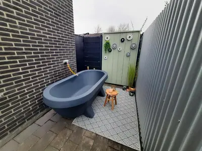 a blue bath tub sitting on a patio next to a brick wall at Vakantievilla 10 km van strand honden welkom omheinde tuin sauna buitenbad in Dirkshorn