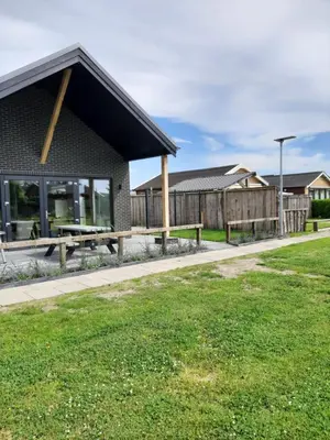a building with a picnic table and a fence at Vakantievilla 10 km van strand honden welkom omheinde tuin sauna buitenbad in Dirkshorn