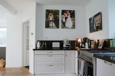 a kitchen with white cabinets and a stove top oven at Dune and Beach Villa with very large and beautiful Garden in Schoorl