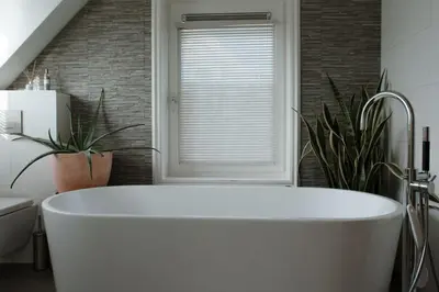a white bath tub in a bathroom with plants at Dune and Beach Villa with very large and beautiful Garden in Schoorl