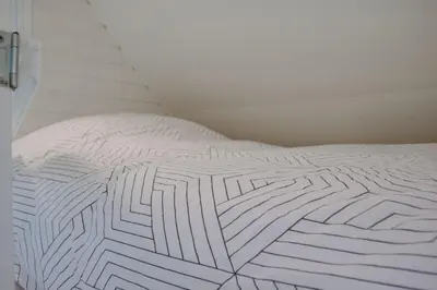 a white comforter with a maze pattern on a bed at Dune and Beach Villa with very large and beautiful Garden in Schoorl