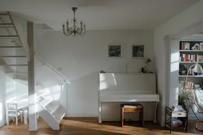 a white piano in a room with a staircase at Dune and Beach Villa with very large and beautiful Garden in Schoorl