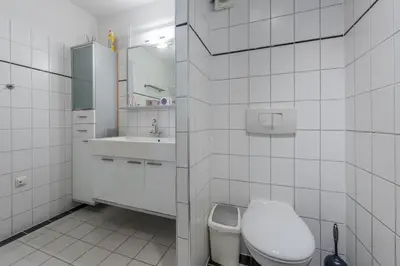 a white bathroom with a toilet and a sink at Villa Noordeinde in Bergen