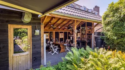 a wooden house with a patio with a table at Villa Noordeinde in Bergen