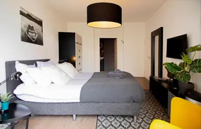 a bedroom with a large bed and a yellow chair at Modern Hideout Ace Location in Amsterdam