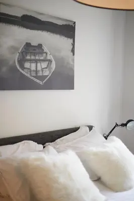 a bed with white sheets and a picture of a boat at Modern Hideout Ace Location in Amsterdam