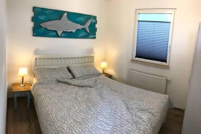a bedroom with a bed and a fish painting on the wall at Ferienhaus Good Times mit eigenem Steg Ferienpark Vislust Ijsselmeer in Wervershoof