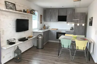 a kitchen with a table and chairs and a television at Ferienhaus Good Times mit eigenem Steg Ferienpark Vislust Ijsselmeer in Wervershoof