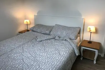 a bedroom with a bed and two lamps on tables at Ferienhaus Good Times mit eigenem Steg Ferienpark Vislust Ijsselmeer in Wervershoof