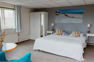 a bedroom with a large white bed and a table at Studio Parkweg in Bergen aan Zee