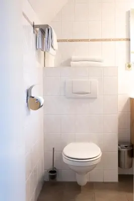 a white bathroom with a toilet and towels at Studio Parkweg in Bergen aan Zee