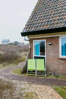 two green chairs sitting outside of a house at Studio Parkweg in Bergen aan Zee