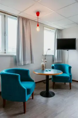a room with two chairs and a table and a tv at Studio Parkweg in Bergen aan Zee