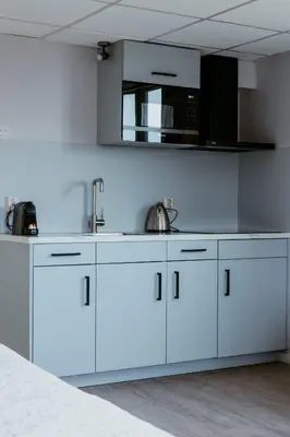 a kitchen with white cabinets and a sink at Studio Parkweg in Bergen aan Zee