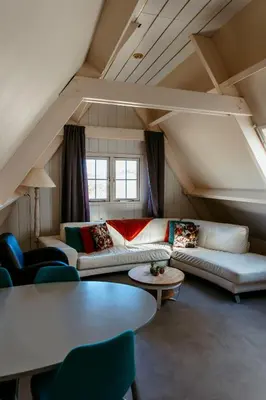 a living room with couches and tables in a attic at Appartement Parkweg in Bergen aan Zee