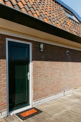 a brick building with a green door on it at Appartement Parkweg in Bergen aan Zee