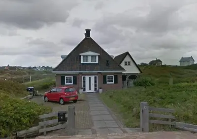 a red car parked in front of a house at Appartement Parkweg in Bergen aan Zee