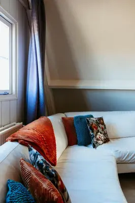 a white couch with colorful pillows on it in a room at Appartement Parkweg in Bergen aan Zee