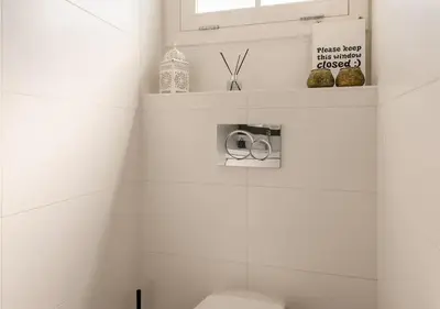 a white bathroom with a toilet and a window at Slaperij ‘t Woud - Near the dunes and the sea! in Bergen