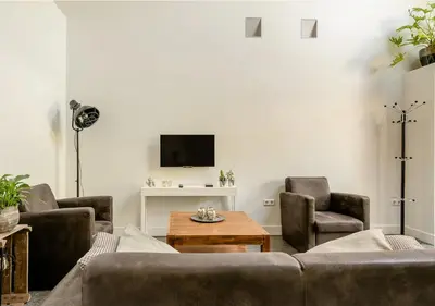 a living room with a couch and chairs and a tv at Slaperij ‘t Woud - Near the dunes and the sea! in Bergen