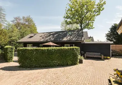 a black house with a hedge in front of it at Slaperij ‘t Woud - Near the dunes and the sea! in Bergen