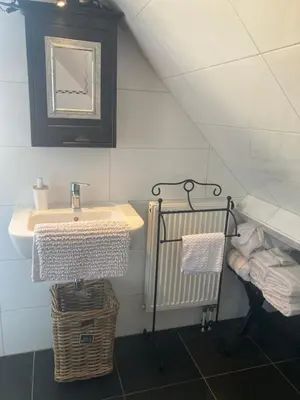 a bathroom with a sink and a mirror and towels at B&BOosterweg3 Studio - Free private parking in Heemskerk