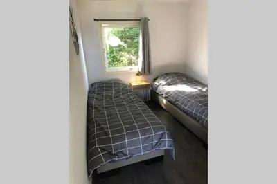 two beds in a small room with a window at Have a nice stay! - Vakantiehuis de Schelp op rustig park in Noordwijk