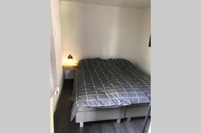 a small bedroom with a bed and a night stand at Have a nice stay! - Vakantiehuis de Schelp op rustig park in Noordwijk