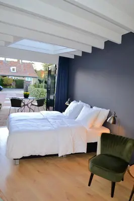a bedroom with a large bed and a green chair at Studio/appartment EVI in Zandvoort