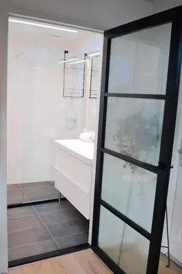 a bathroom with a white sink and a glass door at Studio/appartment EVI in Zandvoort