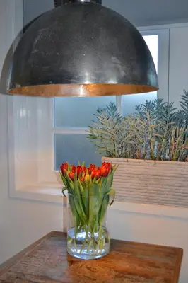 a vase of flowers on a table under a lamp at Studio/appartment EVI in Zandvoort