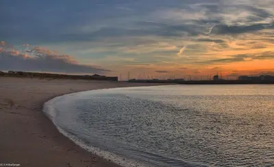 a view of a beach at sunset with a city in the background at Luxe Chalet Marbella IJmuiden aan Zee in IJmuiden