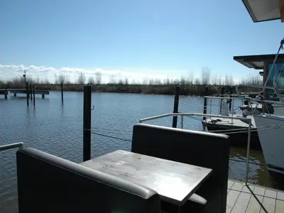 a table and chairs sitting on a dock in the water at Boat in Volendam near Marina Museum in Volendam