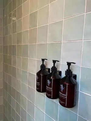 three bottles of soap sitting on a tile wall at Relais & Châteaux Weeshuis Gouda in Gouda
