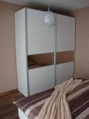 a bedroom with a bed with a large white cabinet at Ferienpark Vislust Modernes Holzhaus am Ijsselmeer mit eigenen Steg in Wervershoof